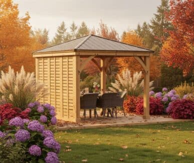 Wooden gazebo with dark metal roof, counter bar, and outdoor seating nestled in a lush UK garden with vibrant autumn foliage.
