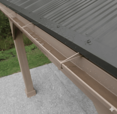Close-up of a functioning pvc gutter system during rainfall, channeling water from a yardistry gazebo with a dark aluminium roof above a concrete base.