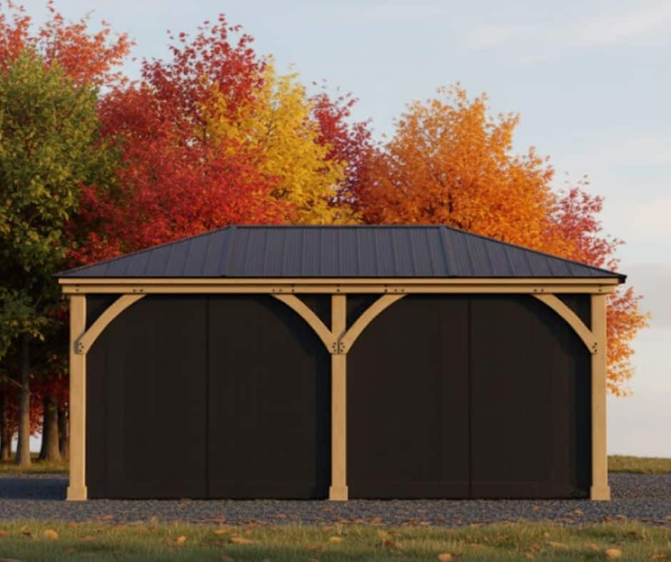 Wooden gazebo with dark metal roof, bar counter, and cushioned seating in a backyard surrounded by vibrant orange and red autumn trees.