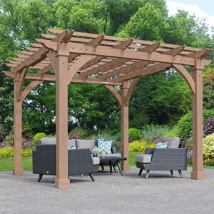 Wooden pergola with slatted roof and cushioned rattan seating, set in a landscaped garden with trees and flowering plants.