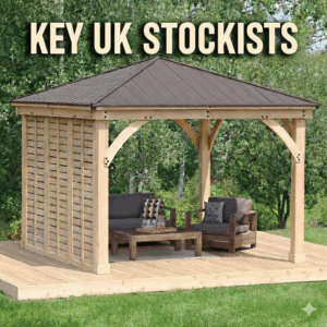 A high-quality, square wooden gazebo with a dark brown metal pyramid roof, situated on a light wood garden deck. The structure features thick timber posts, curved support braces, and a decorative louvered privacy wall on the left side. Underneath the gazebo, there is a modern outdoor seating area with a dark grey sofa, a matching armchair with patterned cushions, and a low wooden coffee table set with glassware. The background is filled with lush green trees and foliage. Large, bold cream-coloured text at the top reads "KEY UK STOCKISTS."